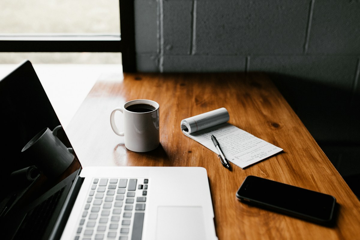 Mesa creativa con portátil, cuaderno y café